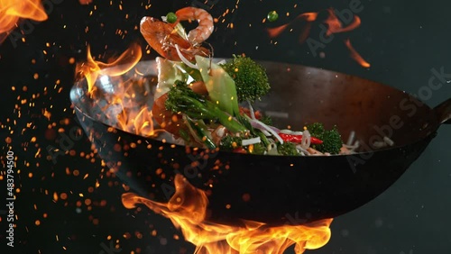 Super Slow Motion Shot of Wok Pan with Flying Ingredients in the Air and Fire Flames. Filmed on High Speed Cinema Camera at 1000 FPS.