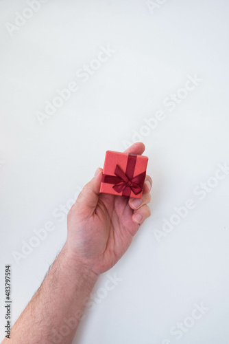 Fototapeta Naklejka Na Ścianę i Meble -  Moscow, Russia, January 2022, male hands on a white background hold a gift tied with a red ribbon