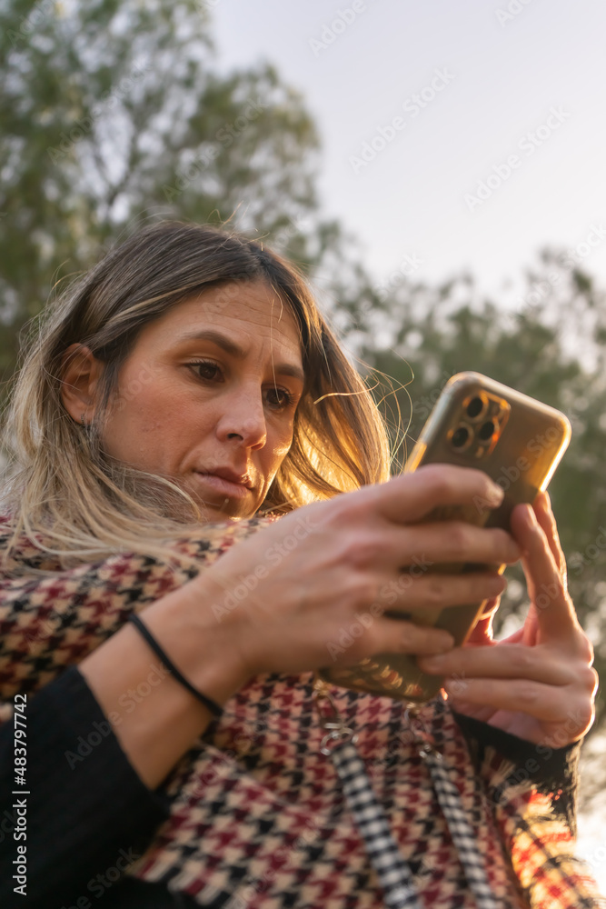 Fototapeta premium Woman using a mobile phone. Business and communication. Woman in the park. Winter day