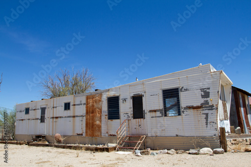 single wide mobile home trailer left in disrepair rusting steel exterior, busted windows, left long abandoned by resident as local economy collapse destroyed mining industry work 