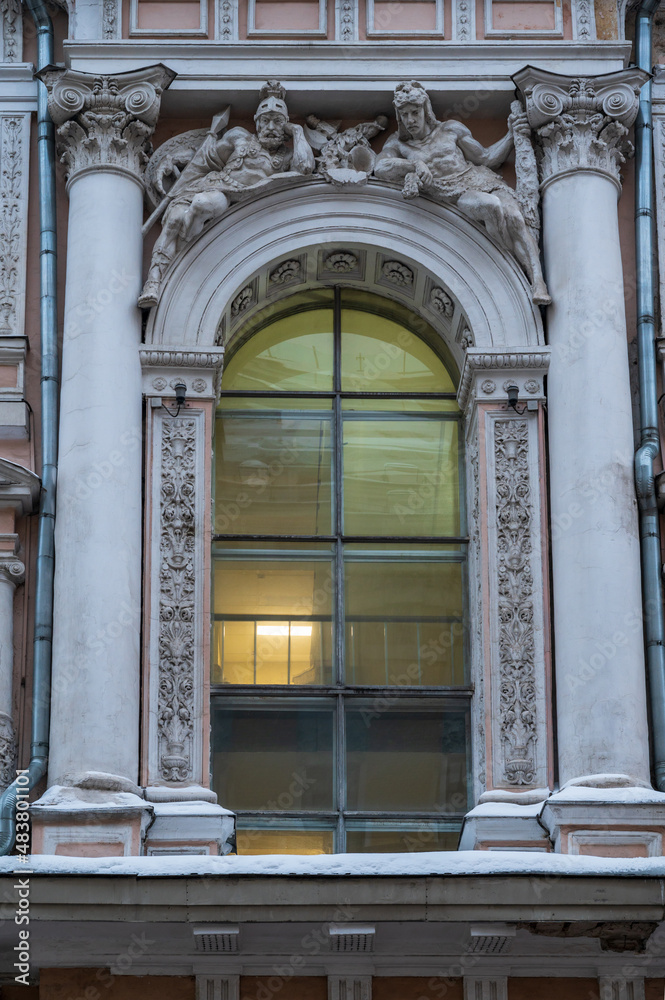 Facade of house decorated with arch, columns and sculptures of warriors, Moscow, Russia