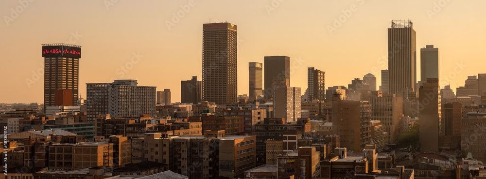 Obraz premium A horizontal panoramic cityscape taken at sunset, of the central business district of the city of Johannesburg, South Africa