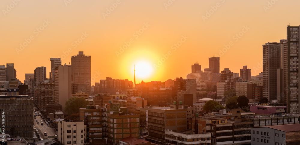 Fototapeta premium A horizontal panoramic cityscape taken at sunset, against an orange sky, of the central business district of the city of Johannesburg, South Africa