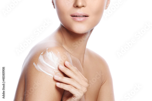 Young and beautiful woman with applying moisturizing cream on her shoulder photo