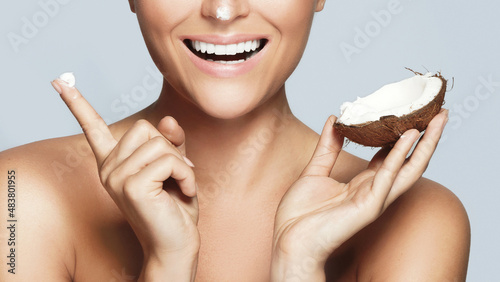 Smiling woman using moisturizing cream based on coconut oil
