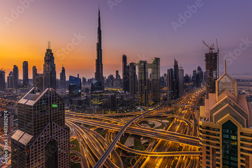 Dubai skyline in the morning. Skyscrapers in downtown Dubai with sunrise. reddish orange colors sky. Road crossing with illuminated lane. Commercial buildings and apartments in the center of Dubai