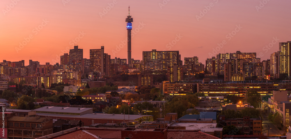 Obraz premium A horizontal panoramic cityscape taken after sunset, of the central business district of the city of Johannesburg, South Africa
