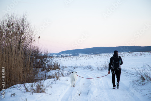 man and his happy white dog enjoying winter snow outdoors on sunny day