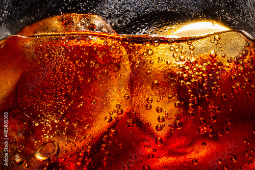 Soft drink glass with ice splash on dark background. Cola glass in celebration party concept.