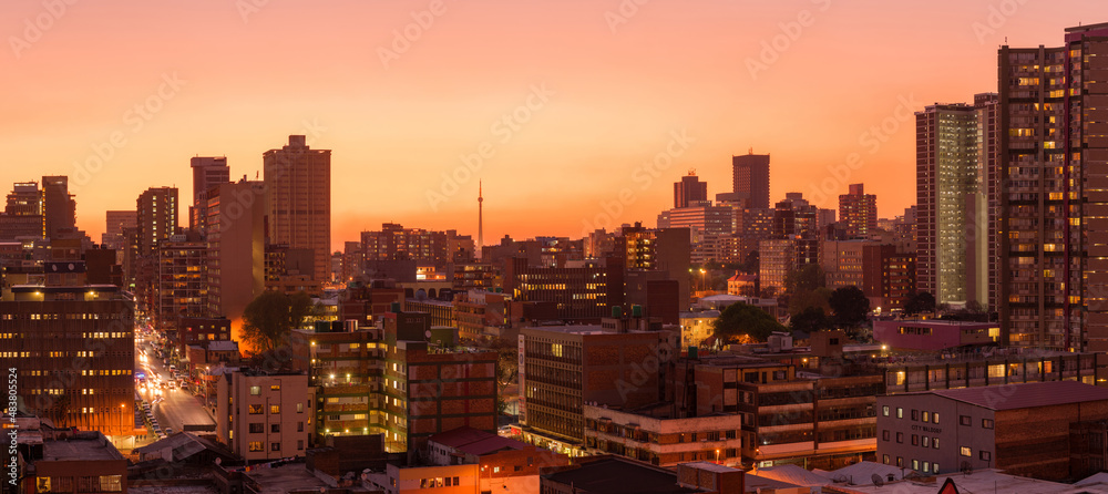 Obraz premium A horizontal panoramic cityscape taken during a golden sunset, of the central business district of the city of Johannesburg, South Africa