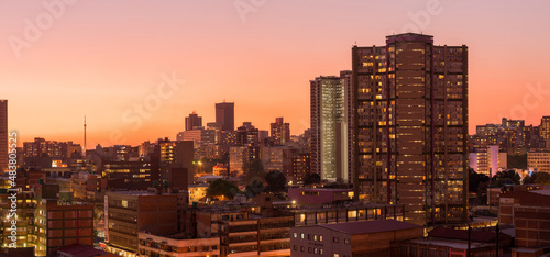 A horizontal panoramic cityscape taken during a golden sunset, of the central business district of the city of Johannesburg, South Africa