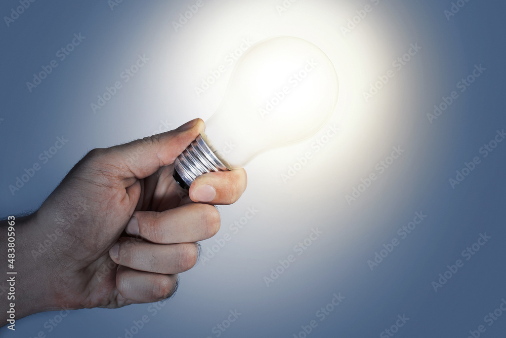 Closeup of male hand holding glowing light bulb Closeup of male hand holding glowing light bulb