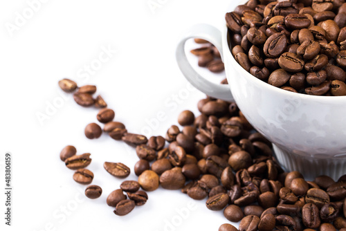 Cup filled with a roasted coffee beans on white background