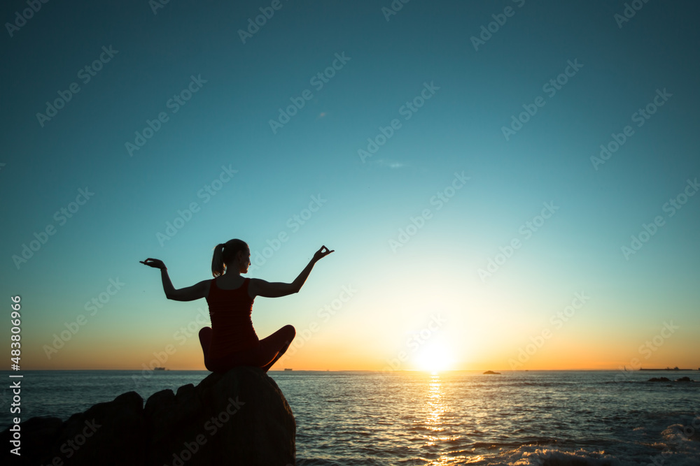 Yoga female meditation on the sea coast during amazing sunset.