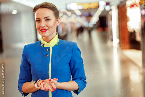 Joyful female flight attendant in stewardess air hostess uniform looking at camera and smiling