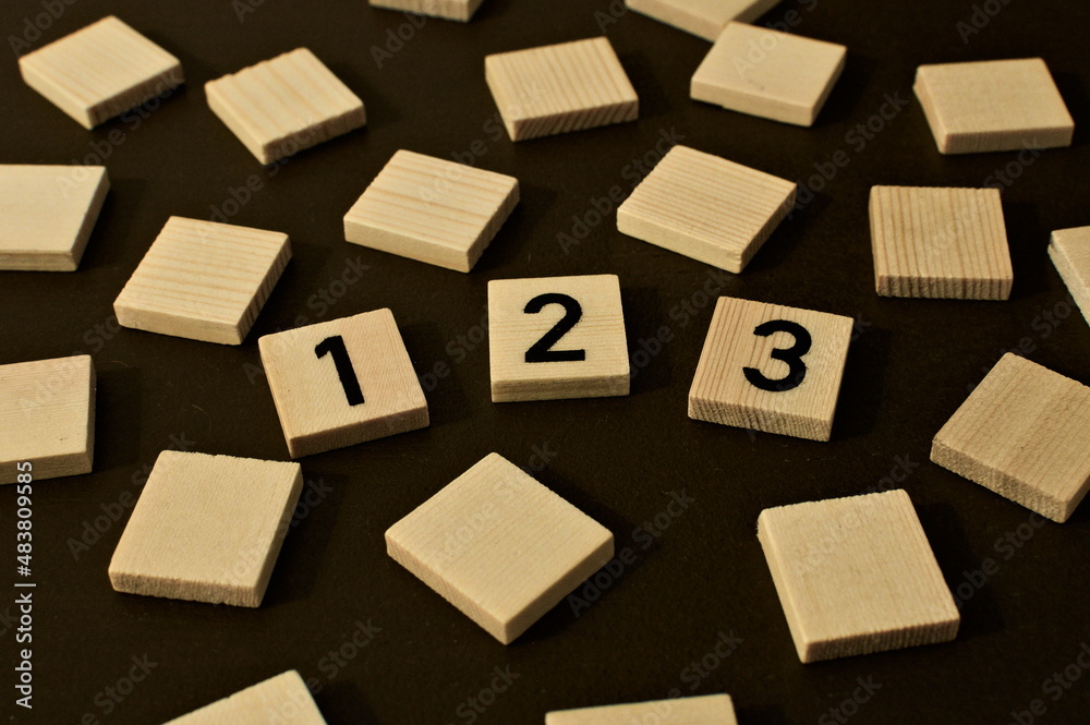 Scattered wooden squares. in the middle write 123 symbolizing e.g. education, numbers or mathematics Scattered wooden squares. in the middle write 123 symbolizing e.g. education, numbers or mathematics