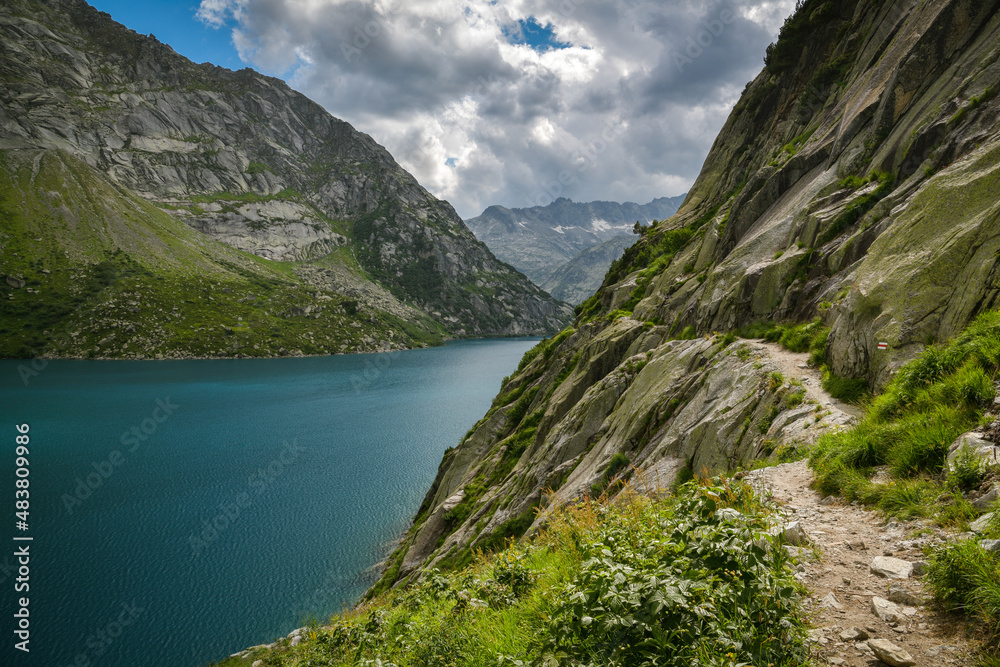 Walking trail next to stone wall above Gelmersee lake in Swiss Alps
