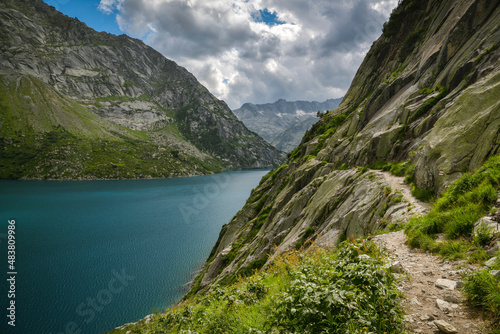 Walking trail next to stone wall above Gelmersee lake in Swiss Alps