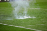 Details with the explosion of a firecracker thrown on the pitch by a supporter during a soccer game.