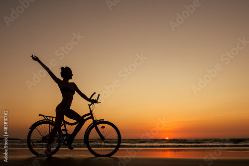 healthy alone woman ride on bicycle on empty sunset Goa India beach