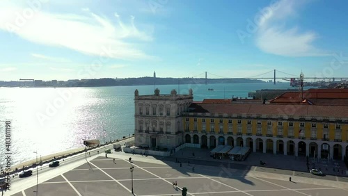Aerial drone view of the Augusta Street Arch from Commerce Square in Lisbon, Portugal. Sunny day with blue sky. Tagus River bridge in the background. (ID: 483811198)