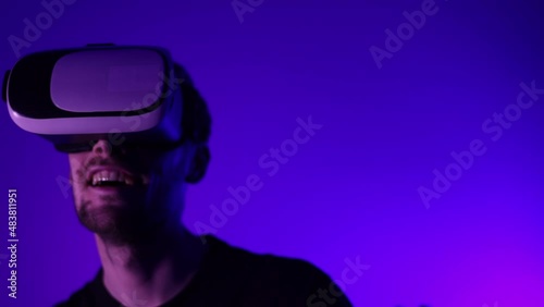 Man in metaverse using VR virtual reality glasses. Futuristic universe games and future in digital technology. Entreatment and NFT in neon colorful space. Happy male. Slow motion video in 3d cyber.