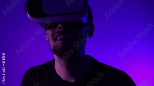 Man in metaverse using VR virtual reality glasses. Futuristic universe games and future in digital technology. Entreatment and NFT in neon colorful space. Happy male. Slow motion video in 3d cyber.