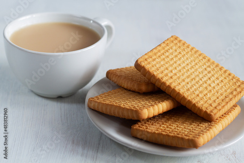 cup of tea and cookies.stacks of tasty cookies with glass of milk on the white plate. square biscuits on the white table with copy space. healthy eating.