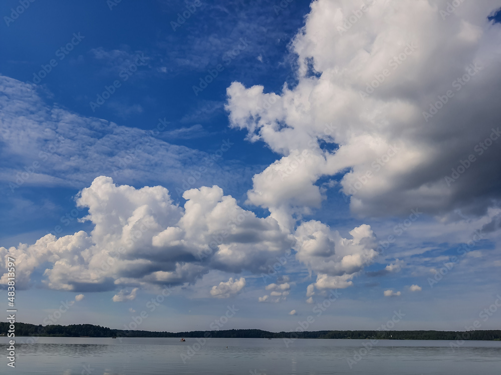 Misty seascape - calm water surface of the lake reflects sky. Altocumulus clouds are full of streaks of beautiful usually appear between lower stratus clouds and higher cirrus clouds