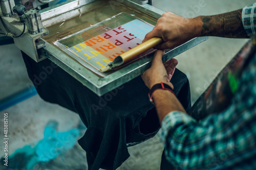 Fotografia Male worker pressing ink on frame while using the printing machine in a workshop
