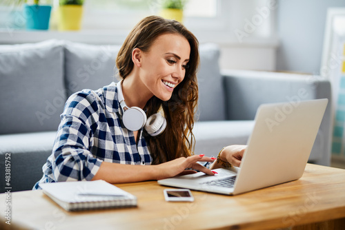 Smiling female student studying on laptop at home