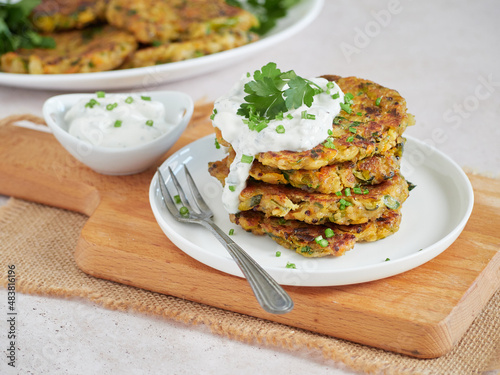 Fotografie vegetable fritters, vegetarian pancakes, served in a pile on a white plate with sour cream and fresh herbs