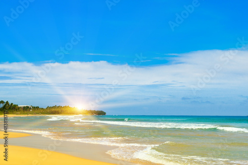 Sandy tropical beach, blue ocean water and bright sun rise.