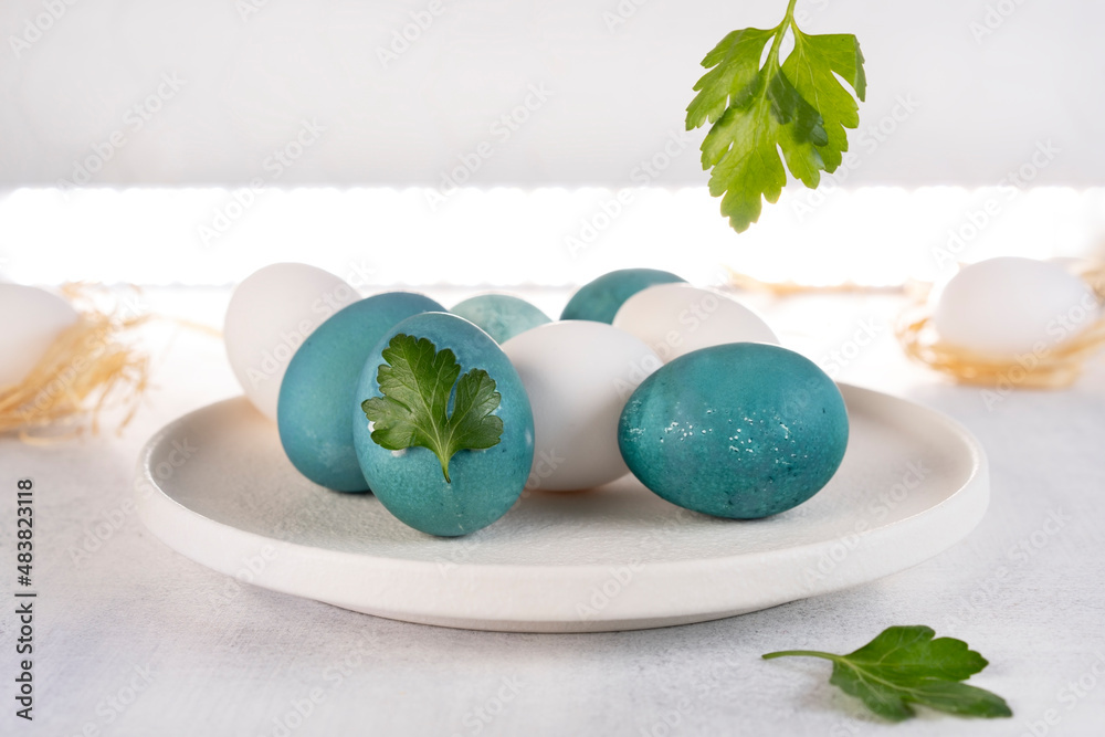 Painting Easter eggs. Natural coloring Easter eggs in blue color. Parsley leaf design.