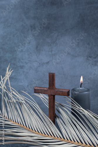 Catholic Cross with palm leaf and burning candle. Ash Wednesday, Lent season, Holy Week, Good Friday and Palm Sunday concept. Copy space. photo