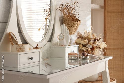 Billede på lærred Wooden dressing table with decorative elements and makeup products in room