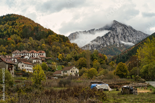 autumnal view of the town of Isaba with the mountain and its peak in the background surrounded by clouds, in the Navarrese Pyrenees