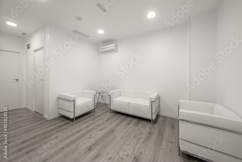 Waiting room in a clinic with air conditioning  white walls and sofas and gray wooden floors