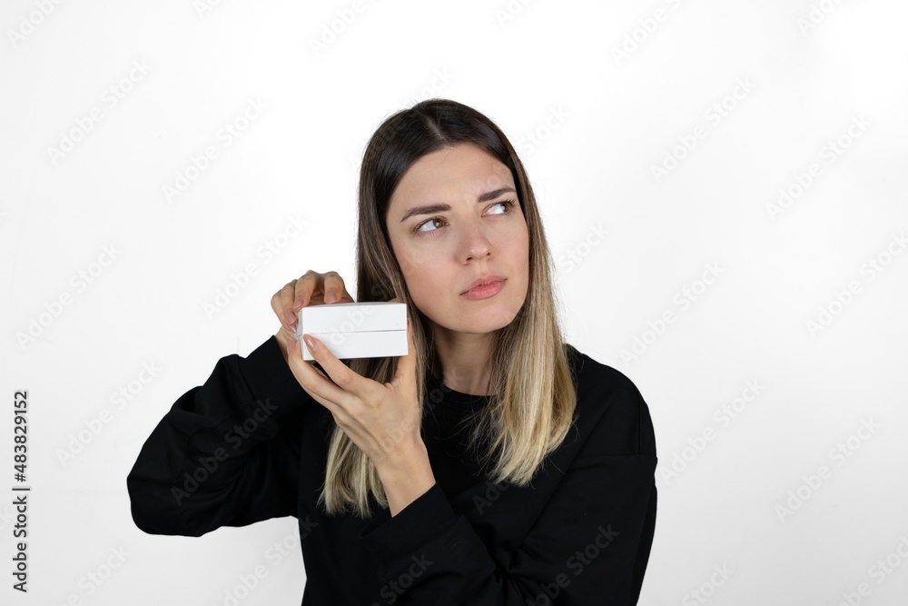 Waist up portrait of pretty young blonde girl in casual clothes trying to guess her present. Isolated on white background. Surprise, jewellery, gift and valentine's day concept. Waist up portrait of pretty young blonde girl in casual clothes trying to guess her present. Isolated on white background. Surprise, jewellery, gift and valentine's day concept.