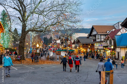 Visitors enjoy the colorful Bavarian themed village of Leavenworth, Washington, USA on a winter evening with lights coming on in the town.