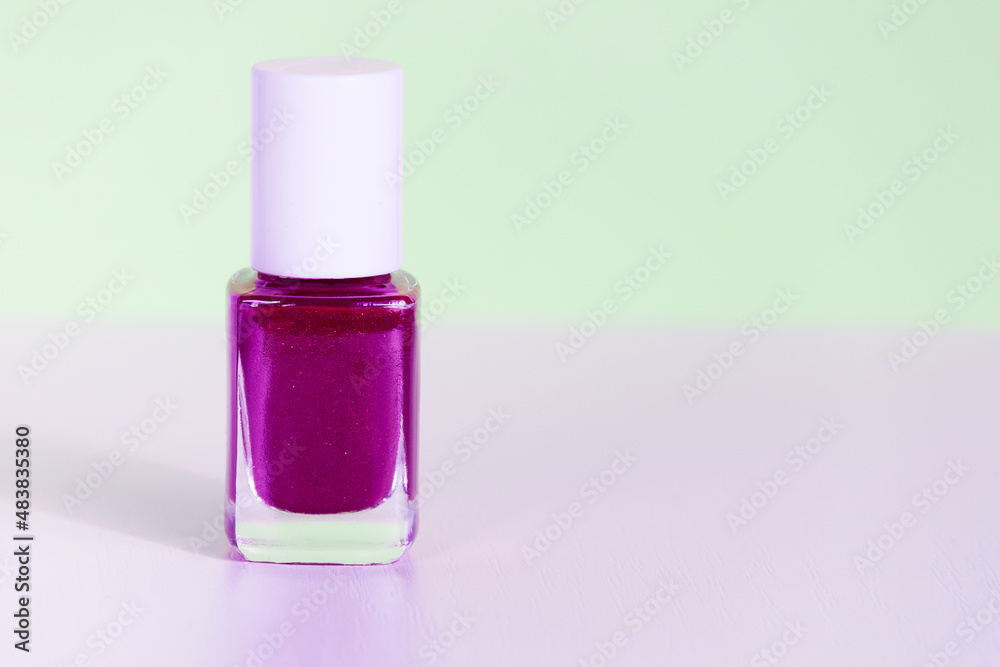 Purple glitter nail polish bottle on neon light, copy space Purple glitter nail polish bottle on neon light, copy space