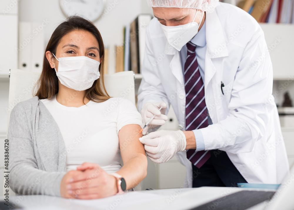 Φωτογραφία Doctor in face mask uses hypodermic needle and a syringe to put a shot of drug t