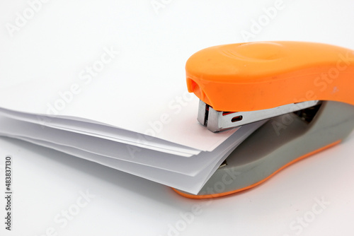 Stapling sheets of paper with an orange stapler photo
