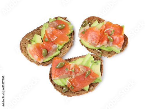 Delicious sandwiches with salmon, avocado and capers on white background, top view