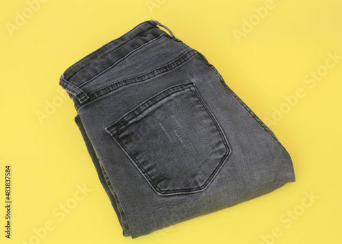 folded blue jeans on a yellow background. modern casual clothing. flat lay, copy space.