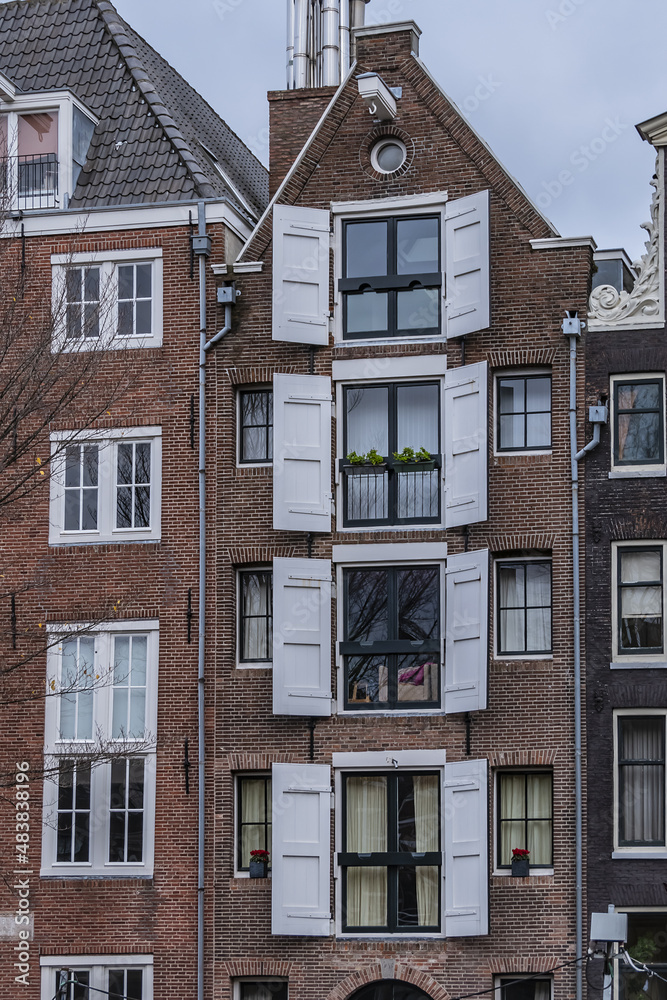 Close-up view details of old colorful building (XVI- XVIII centuries) with gable rooftop and hook along Prince's Canal (Prinsengracht) canal in Amsterdam. Amsterdam, the Netherlands. Close-up view details of old colorful building (XVI- XVIII centuries) with gable rooftop and hook along Prince's Canal (Prinsengracht) canal in Amsterdam. Amsterdam, the Netherlands.
