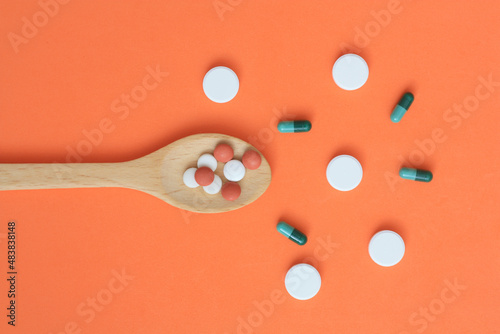 color medical capsules on wooden spoon photo