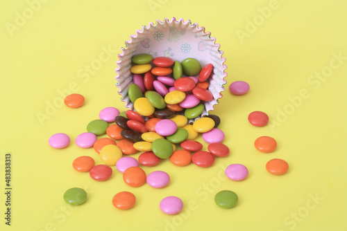 Bright multi colour chocolate gemes on yellow background. photo