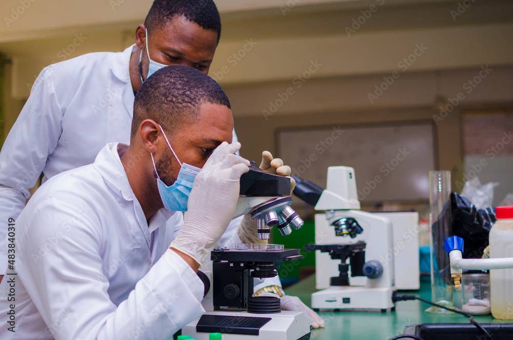 Scientists studying a virus ,looking through microscope