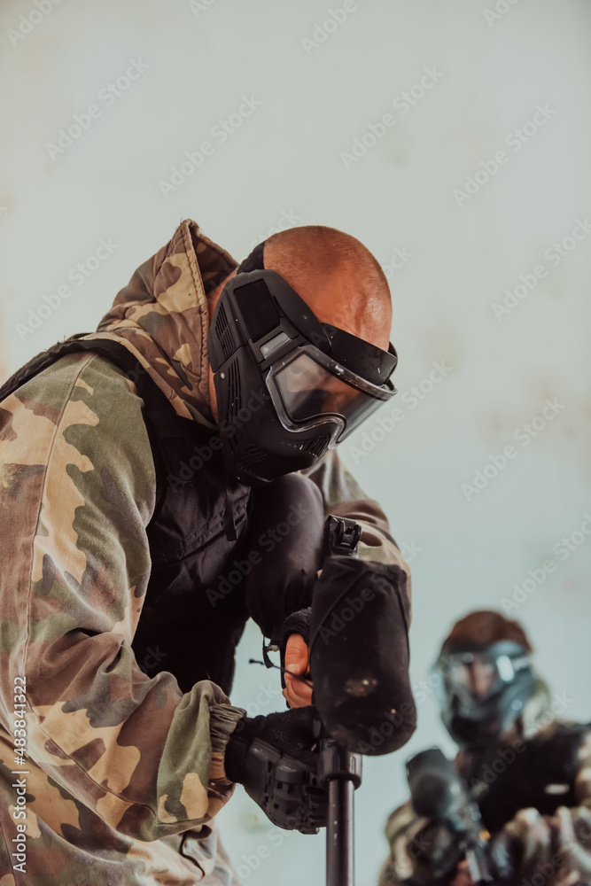 Paintball player in mask who is aiming in opponents at paintball arena. Selective focus Paintball player in mask who is aiming in opponents at paintball arena. Selective focus